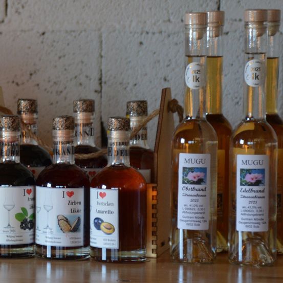 Mehrere Flaschen Likör sind auf einem Holztisch aufgereiht. Die Flaschen haben Korkverschlüsse und Etiketten mit Namen wie 'Ich liebe schwarze Johannisbeerlikör', 'Ich liebe schwarze Johannisbeerlikör' und 'Ich liebe Amaretto'.