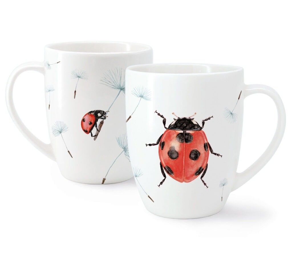 Zwei weiße Kaffeebecher mit Marienkäfern und Löwenzahn. Ein Becher zeigt einen Marienkäfer, der einen Löwenzahn hält, der andere einen fliegenden Marienkäfer.