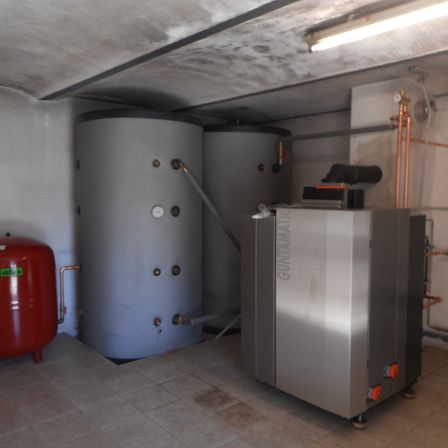 Ein Raum mit zwei großen Wassertanks und einem Gerät aus Gunmetal, beleuchtet von einer Deckenlampe.