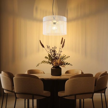 Ein Esszimmer mit einem runden Tisch und Stühlen darum. Eine Pflanze in einem Vasen steht auf dem Tisch, und eine Lampe hängt von der Decke.