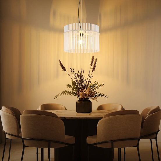 Ein Esszimmer mit einem runden Tisch und Stühlen darum. Eine Pflanze in einem Vasen steht auf dem Tisch, und eine Lampe hängt von der Decke.