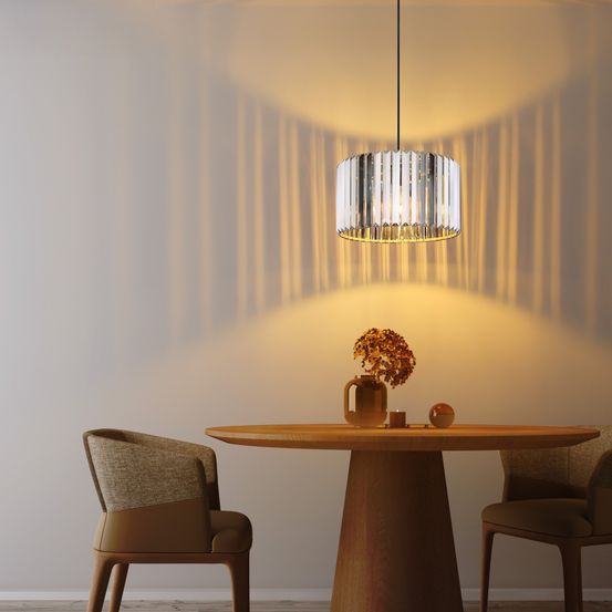 Ein Essbereich mit einem runden Holztisch, zwei Stühlen und einer Pendelleuchte. Ein Vasen mit Blumen, eine Kerze und eine Glaskugel sind auf dem Tisch.