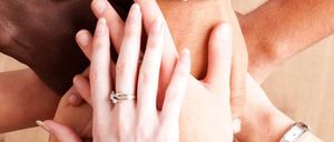 Vier Menschen halten sich an den Händen, drei tragen Armbänder und einer eine Uhr.