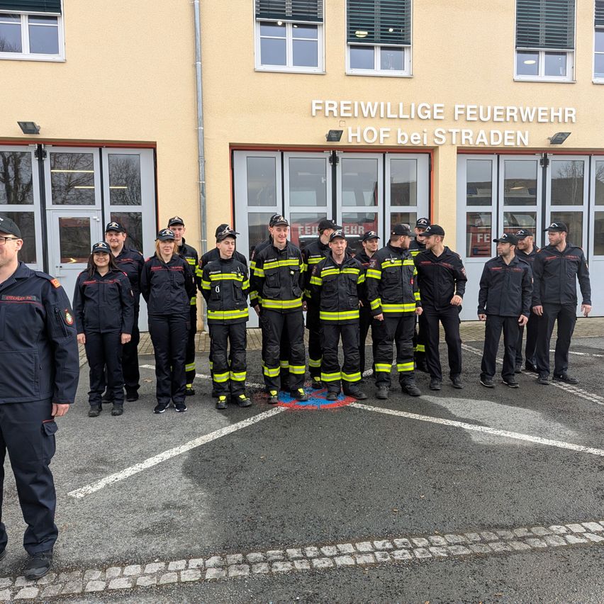 A group of firefighters in uniform stands in front of a building with the text Freiwillige Feuerwehr Hof bei Straden.