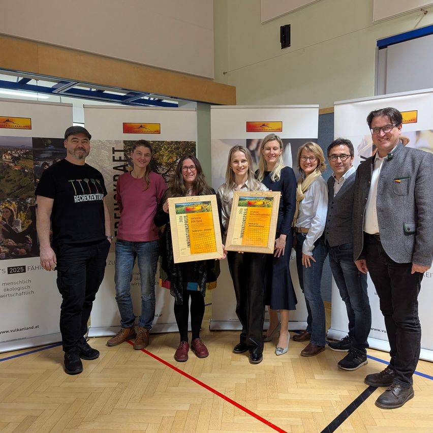A group of people standing together holding certificates in a room with a red line on the floor.