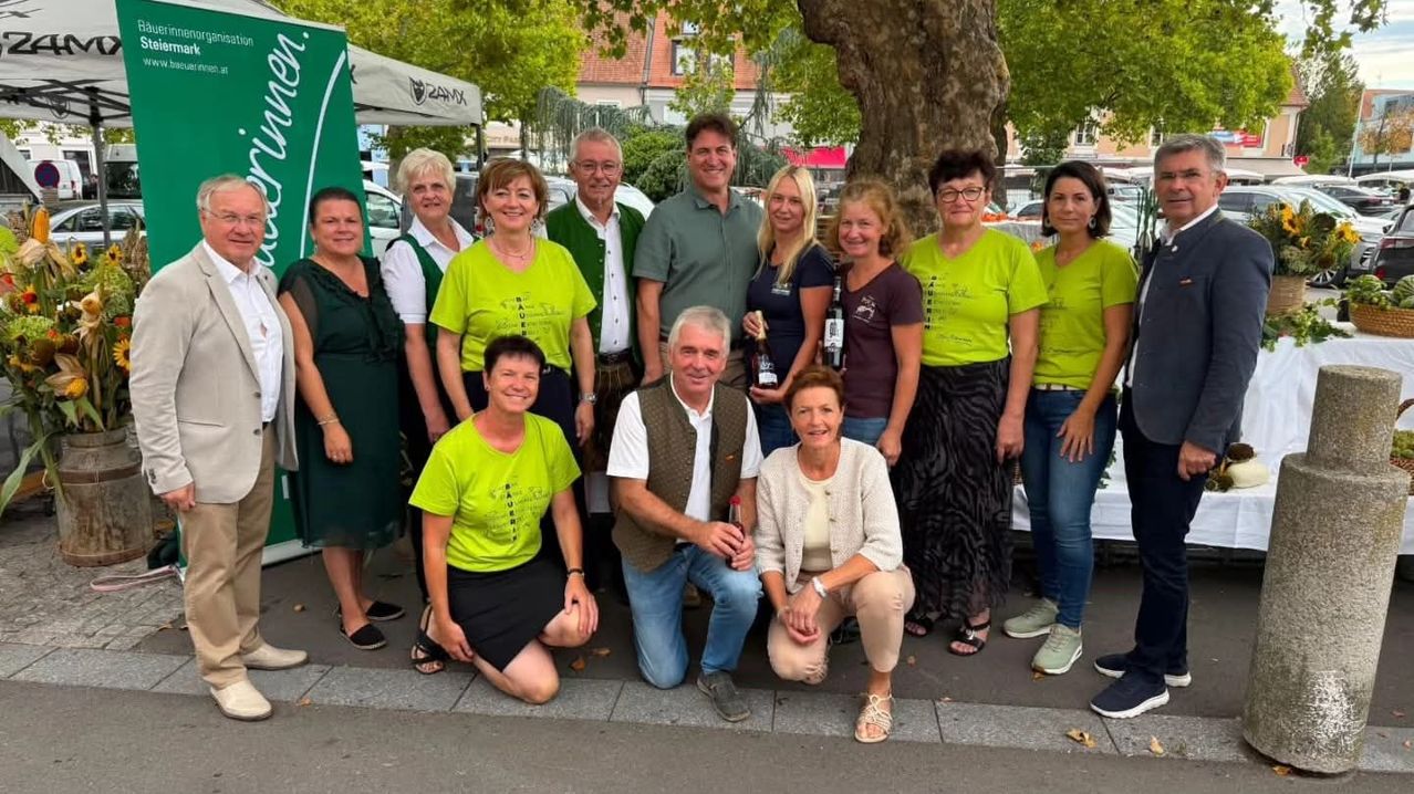A group of people in green shirts are posing for a photo in front of a tree.