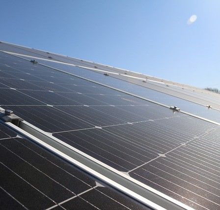 Ein Nahaufnahme einer Solarpanelanlage, die auf dem Dach eines Gebäudes unter einem klaren blauen Himmel montiert ist.