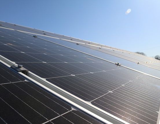 Ein Nahaufnahme einer Solarpanelanlage, die auf dem Dach eines Gebäudes unter einem klaren blauen Himmel montiert ist.