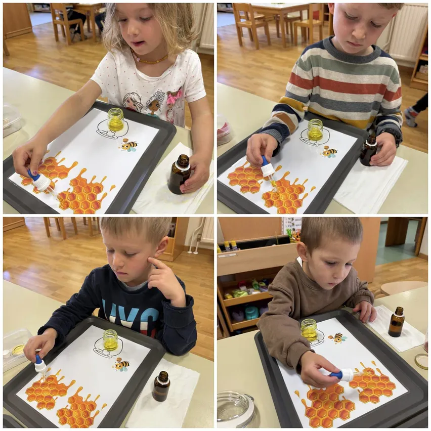 Vier Kinder sind in einer Kunstaktivität an Tischen beschäftigt. Jedes Kind verwendet einen Pinsel, um gelbe Flüssigkeit aus einer kleinen Flasche auf ein Blatt mit einem Honigwabenmuster aufzutragen.