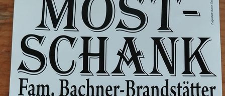 A poster advertising Must-Schänk by Fam. Bachner-Brandstätter. Address: 8244 Schäffern, Dorfstraße 11. Phone: 0 33 39 / 73 44. Event: April 17 to May 4, 2026. Home-made products.