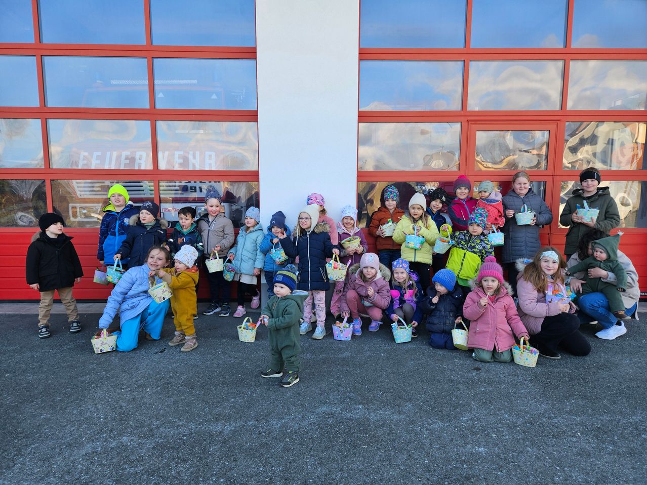Group of children posing for a photo with Easter baskets outside a fire station.