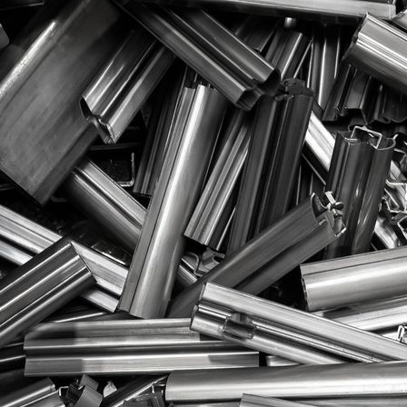 Ein monochromes Bild zeigt einen Haufen metallischer Rohre und Stäbe in verschiedenen Längen und Formen.