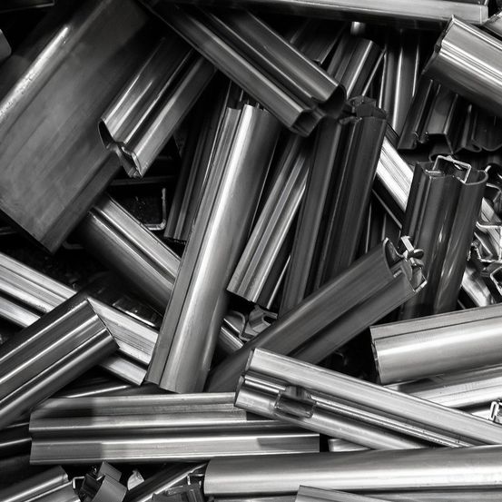 Ein monochromes Bild zeigt einen Haufen metallischer Rohre und Stäbe in verschiedenen Längen und Formen.