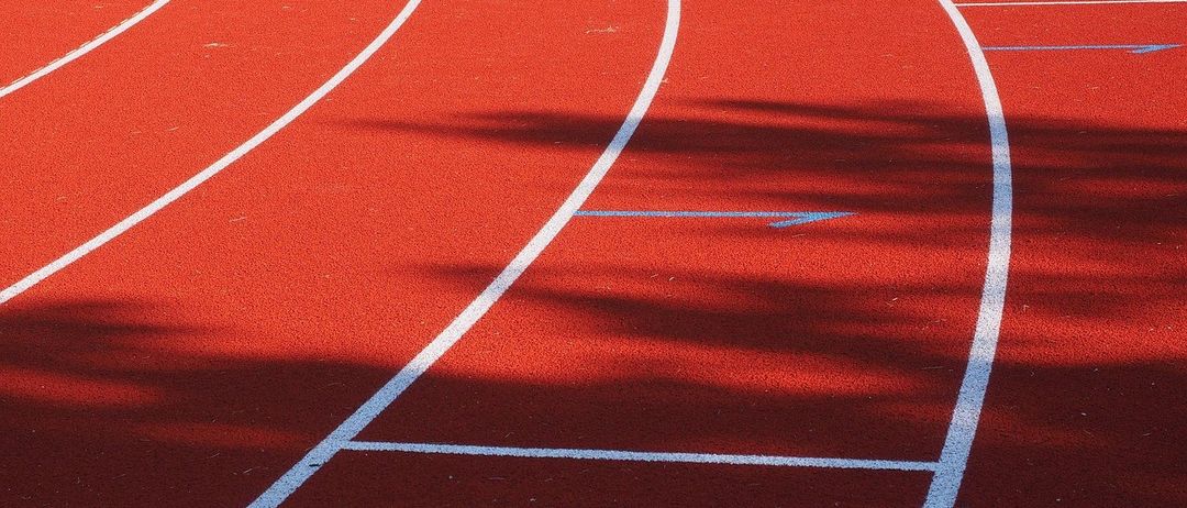 Eine rote Laufbahn mit weißen Linien und einem blauen Pfeil an der Seite.