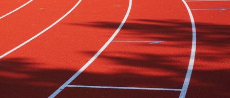 Eine rote Laufbahn mit weißen Linien und einem blauen Pfeil an der Seite.