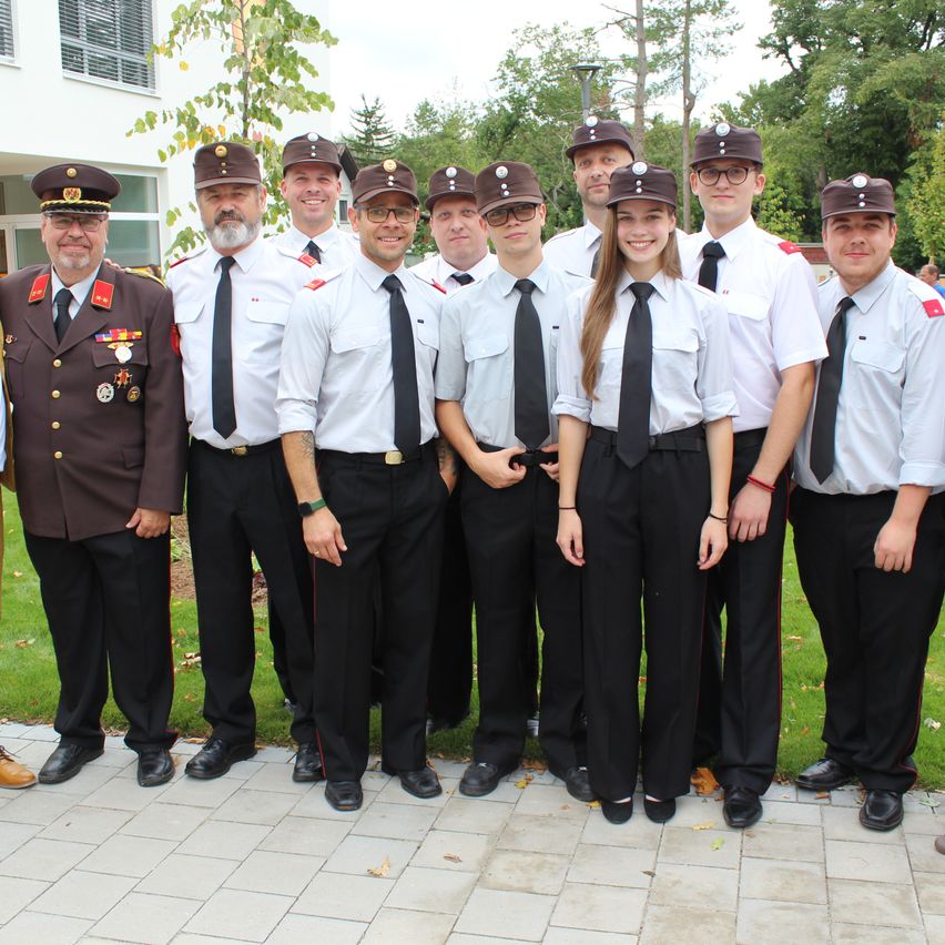 A group of uniformed individuals stand in a row, wearing hats and ties. They appear to be part of a formal event or organization, possibly a military or police unit.