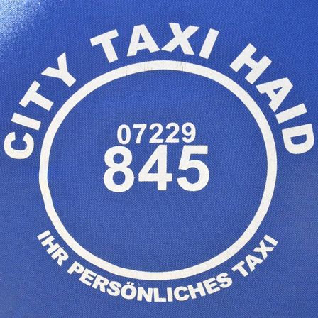 Ein blaues Logo eines Taxi-Dienstes mit dem Namen City Taxi Haid. Es zeigt die Kontaktnummer 07229 845 in weiß. Darunter steht 'IHR PERSONLICHES TAXI'.