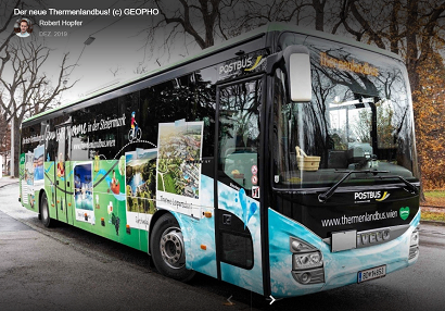 Ein moderner, großer blau-grüner Bus mit der Aufschrift 'Postbus' auf der Vorderseite steht am Straßenrand. Er hat ein Nummernschild mit der Aufschrift '85-HB-51'.