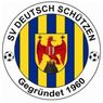 Logo of SV Deutsch Schützen, founded in 1960, featuring a shield with a red eagle, cross, and a mountain, set against blue and yellow stripes, with soccer balls on the sides.