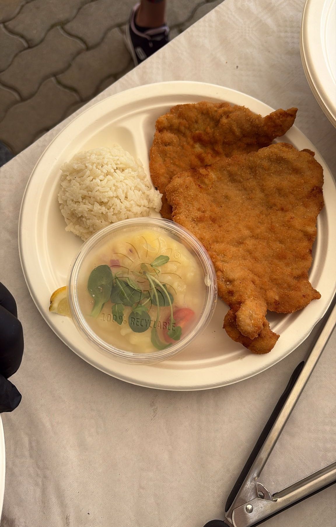 A plate of fried breaded meat, rice, and a bowl of soup with greens and a lemon slice.