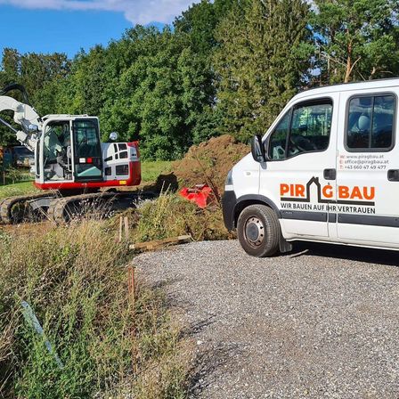 Ein roter und weißer Bagger steht auf einem Kiesweg neben einem weißen Van mit der Aufschrift 'PIR G BAU'. Im Hintergrund befinden sich Bäume und Büsche.