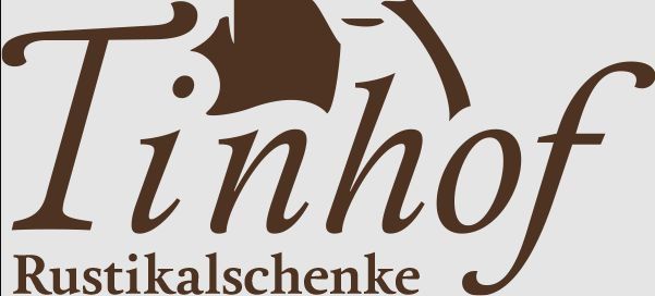 Das Logo für Tinhof Rustikalgeschenke, mit stilisiertem Text, geschwungenem Design und zentralem Bild einer Fledermaus.