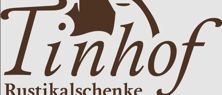 Das Logo für Tinhof Rustikalgeschenke, mit stilisiertem Text, geschwungenem Design und zentralem Bild einer Fledermaus.