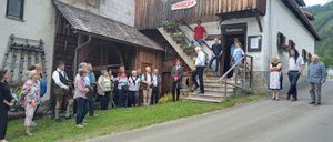 Eine Gruppe von Menschen steht vor einem Holzgebäude mit dem Schild Museum. Sie sind wahrscheinlich Touristen. Einige betrachten die Blumen.