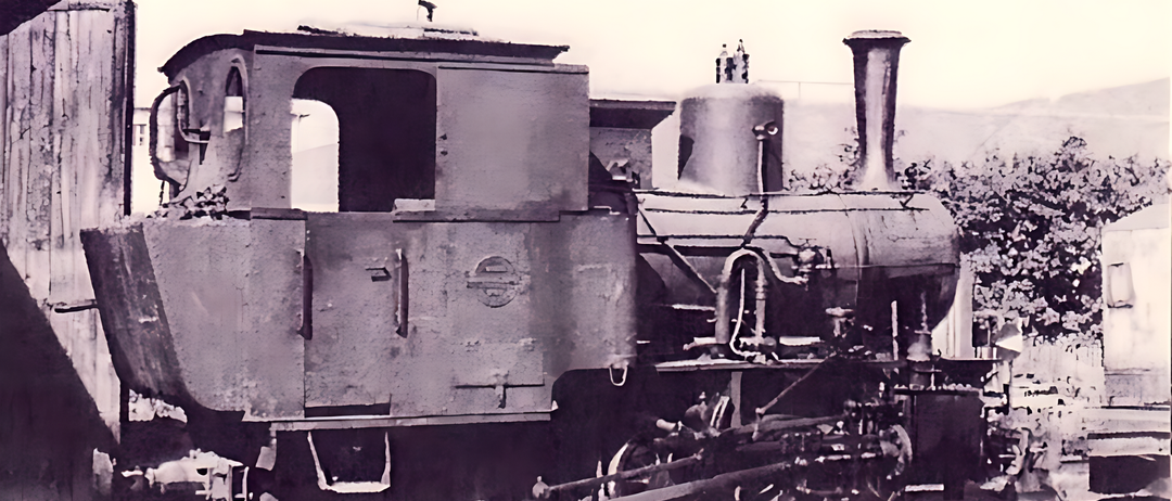 Ein altes Schwarz-Weiß-Bild einer Vintage-Dampflokomotive mit einem großen Kessel und einem Schornstein vorne.