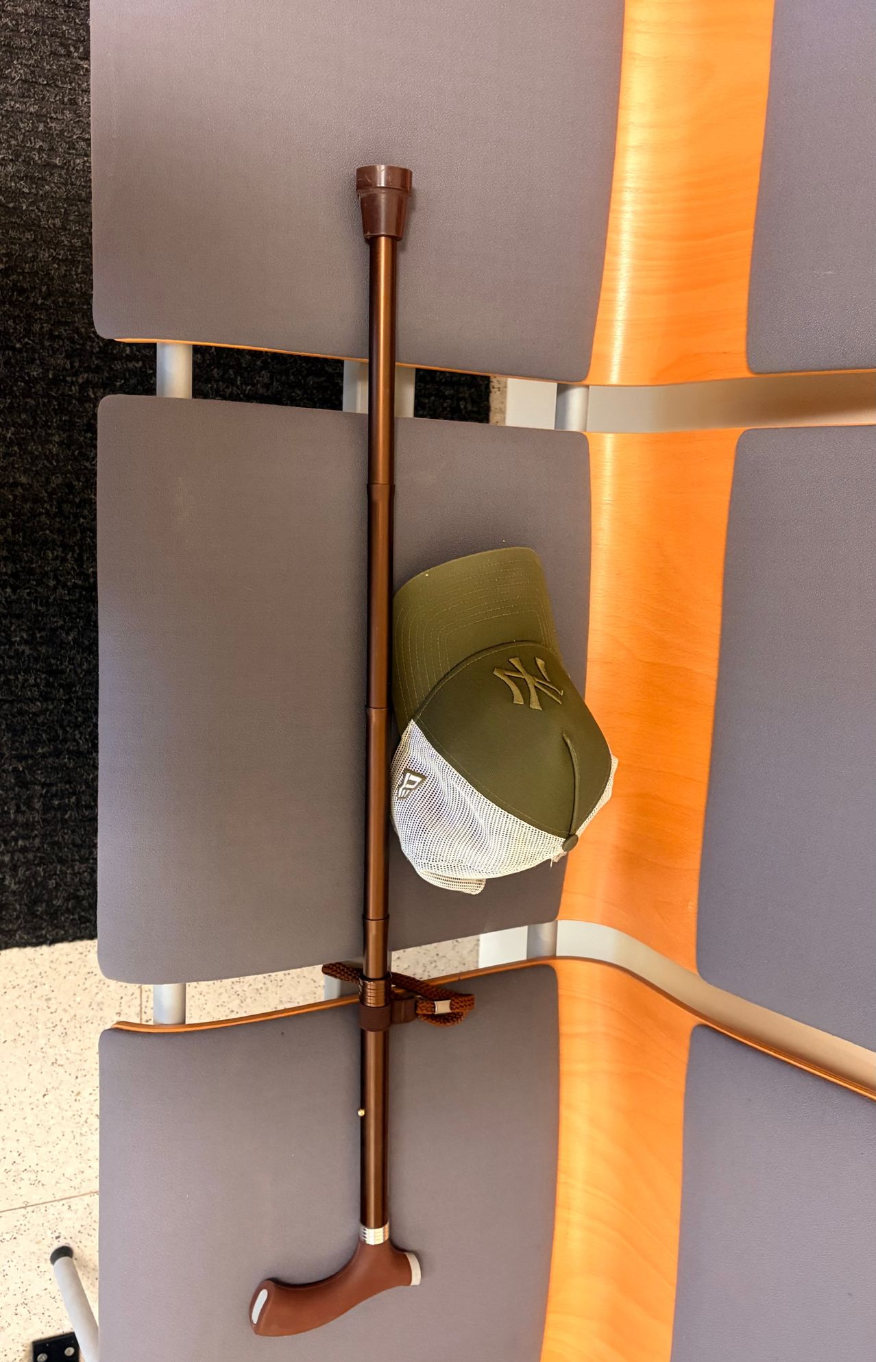 A green and white baseball cap hangs on a metal pole between two gray chairs. The cap features the New York Yankees logo.