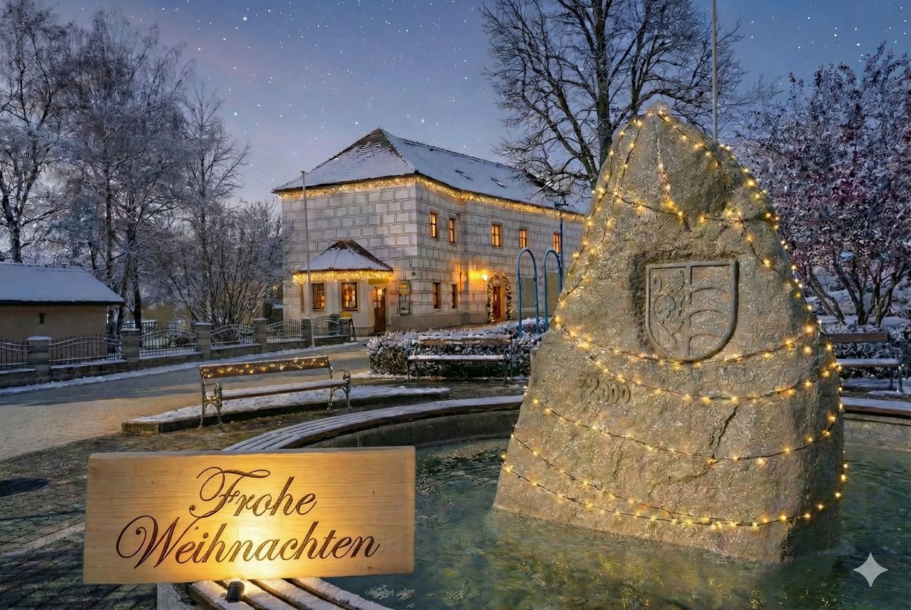Ein Haus mit schneebedecktem Dach und Weihnachtslichtern leuchtet bei Nacht. Ein Stuhl steht in der Nähe mit einem Schild, das 'Frohe Weihnachten' besagt. Ein Brunnen hat ein Steinmonument, das mit Lichtern geschmückt ist.