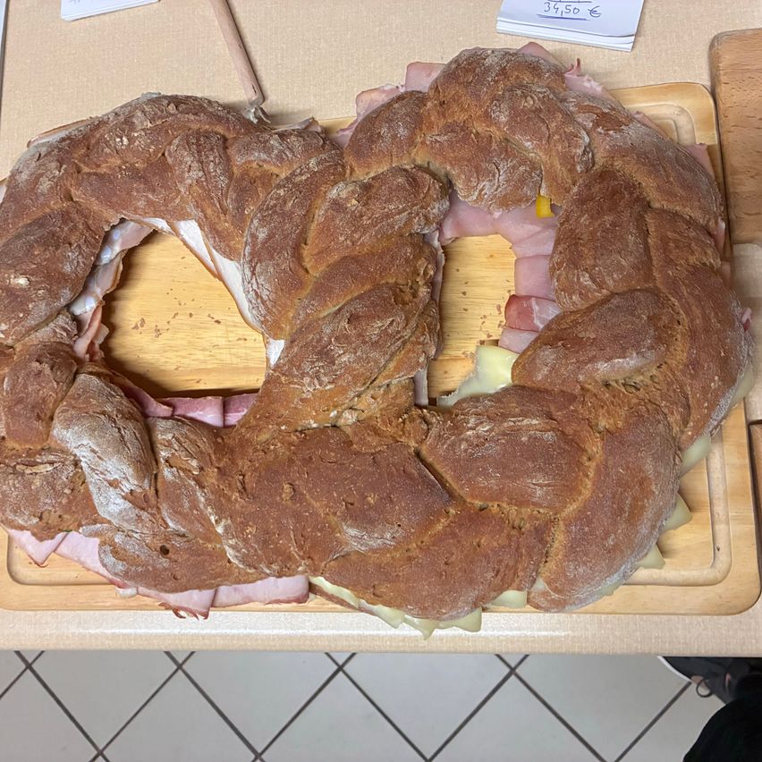 Ein geflochtener Brotlaib mit Schinken- und Käsefüllung, aufgeschnitten und auf einem Holzschneidebrett präsentiert, zum Preis von 39,50 Euro.