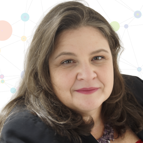 Eine Frau mit braunen Haaren und rosa Lippenstift lächelt in die Kamera, trägt einen schwarzen Blazer und eine lila Halskette. Der Hintergrund zeigt ein farbenfrohes, abstraktes Design.