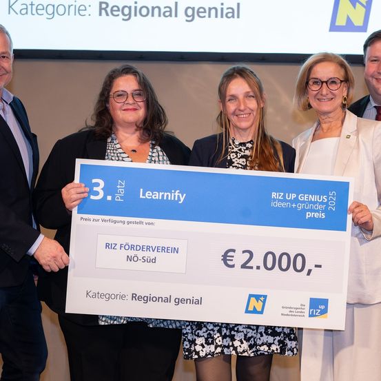 Eine Gruppe von vier Personen hält einen großen Scheck über 2.000 Euro, der für eine regionale Initiative vergeben wurde. Sie stehen lächelnd da und befinden sich wahrscheinlich bei einer Preisverleihung.