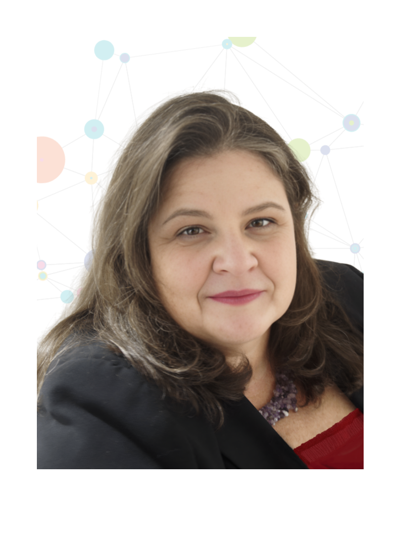 Eine lächelnde Frau mit braunem Haar, die einen schwarzen Blazer und ein rotes Oberteil trägt, schaut direkt in die Kamera.