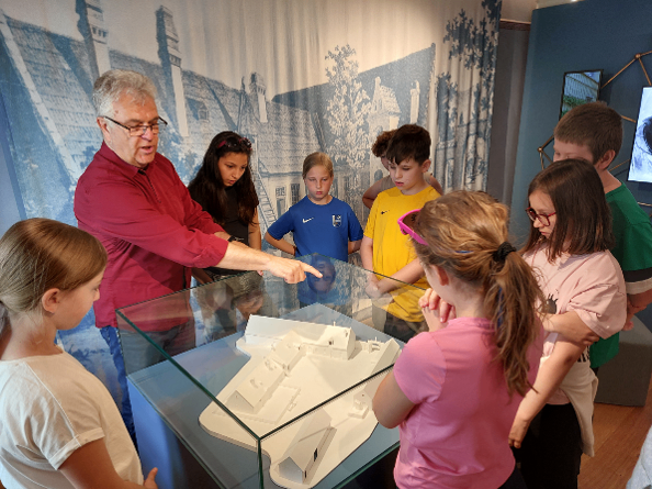 Museumsführer erklärt Kindern ein Modell in einem Ausstellungsraum in Österreich.