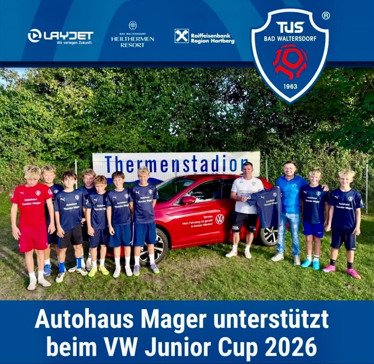 A group of young soccer players stands in front of a red car with Autohaus Mager's logo, with a banner reading 'Thermenstadion'. They are wearing blue uniforms and holding jerseys. The image also includes logos for LayJet, Heithermen Resort, and Raiffeisenbank.
