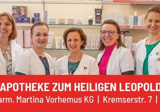 Fünf Frauen in weißen Laborkitteln stehen vor einer Apotheke mit Regalen voller Produkte im Hintergrund. Der Text lautet Stadtapotheke zum Heiligen Leopold.