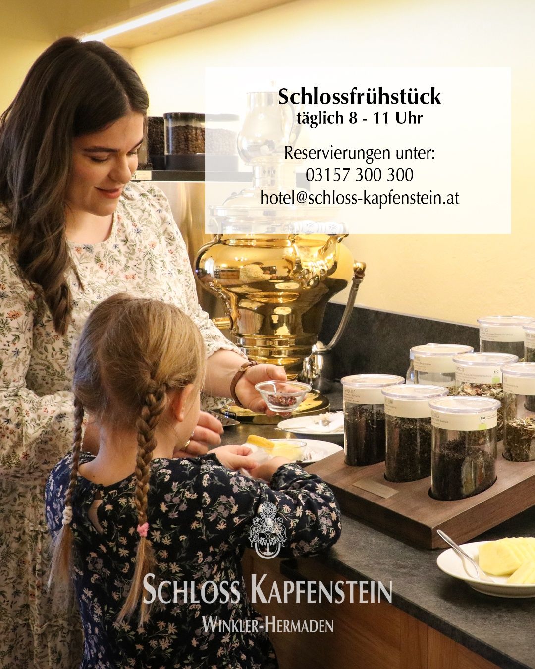 Eine Frau und ein junges Maßchen stehen an einer Theke in einem Hotel und bereiten ein Getränk zu. Ein Schild darüber lautet 'Schloßfrühstück täglich 8 - 11 Uhr'.