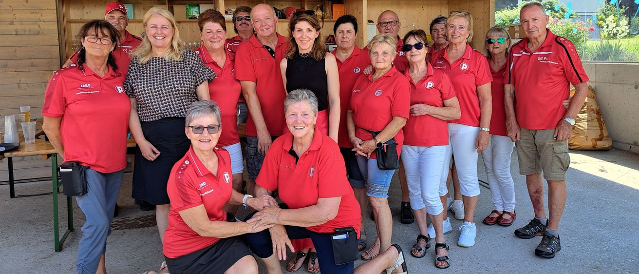Eine Gruppe von Menschen in roten Shirts posiert für ein Foto in einem Schuppen.