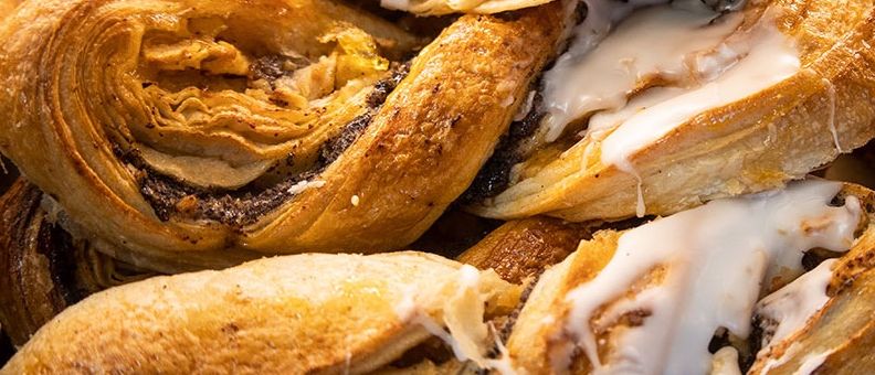 Ein Nahaufnahme von verschiedenen Gebäcksorten, darunter Zimtschnecken und Croissants, wobei eine Gebäcksorte aufgeschnitten ist, um ihre Füllung zu zeigen.