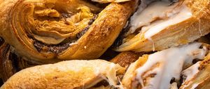 Ein Nahaufnahme von verschiedenen Gebäcksorten, darunter Zimtschnecken und Croissants, wobei eine Gebäcksorte aufgeschnitten ist, um ihre Füllung zu zeigen.