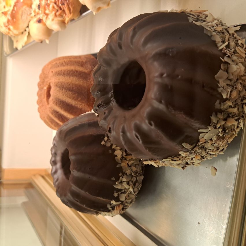 Drei Schokoladen-Desserts mit verschiedenen Toppings auf einem Metalltablett. Das mittlere hat ein Loch in der Mitte.