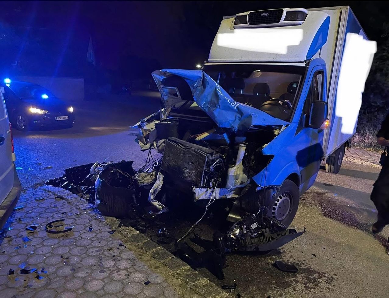 Ein schwer beschädigtes Fahrzeug steht auf der Straße mit zertrümmerter Front, möglicherweise durch einen Hochgeschwindigkeitszusammenstoß.
