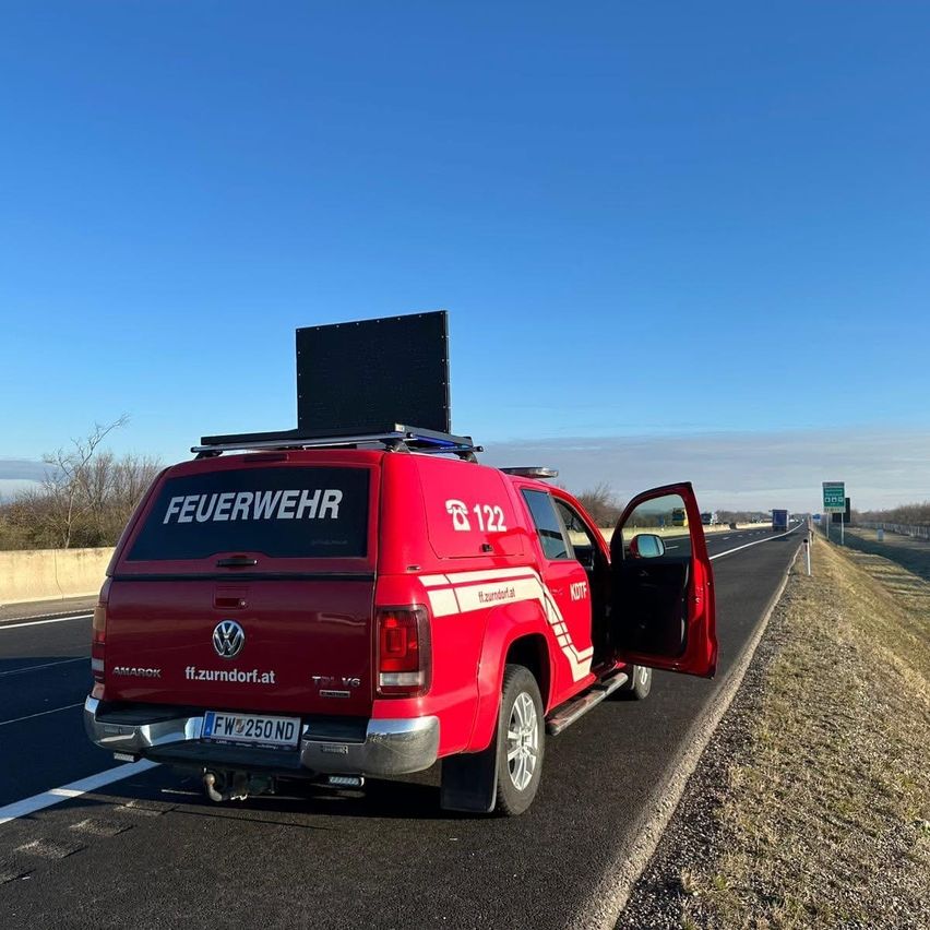 Ein roter Volkswagen Amarok mit dem Logo der Feuerwehr und der Nummer 122 steht am Straßenrand einer Autobahn.