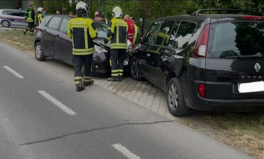 Emergency responders at a car accident scene with two damaged cars, firefighters, and police.