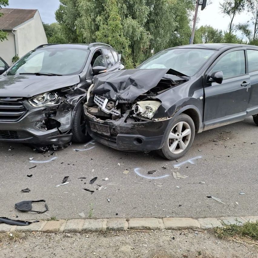 Unfall: Zwei stark beschädigte Autos stehen auf einer Straße, Trümmerteile liegen herum.