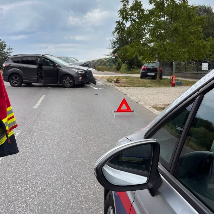 Unfallstelle mit einem beschädigten SUV auf der Straße, einem Feuerlöscher am Bürgersteig und einem geparkten Polizeiwagen in der Nähe.
