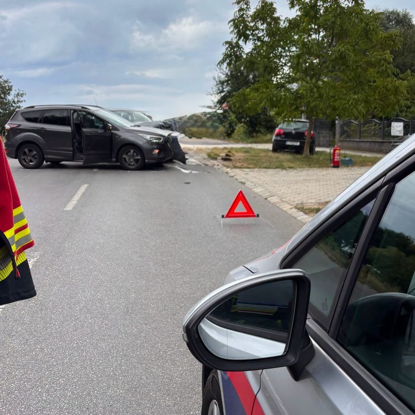 Unfallstelle mit beschädigten Autos, Warndreieck und Feuerlöscher auf nasser Straße