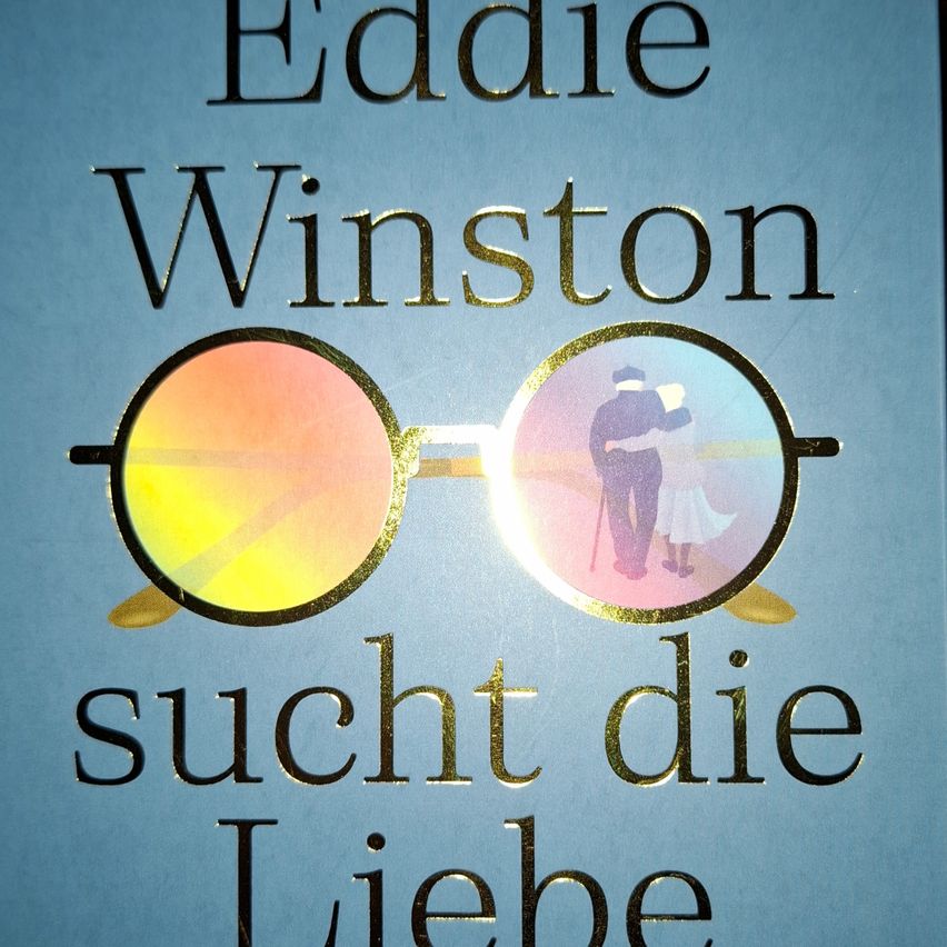 Buchcover von 'Eddie Winston sucht die Liebe' zeigt einen älteren Mann und ein Kind am Strand mit einem Paar goldgerahmter Gläser im Vordergrund.